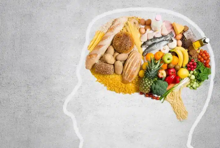 A photo of a person's head's outline on a wall. The head has various healthy food items inside suggesting mindful eating on International Yoga Day 2023.