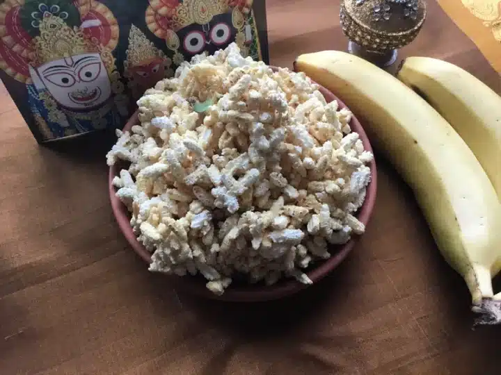 A shot of a traditional Rath Yatra Chappan Bhog food Ukhuda served on a round bowl. There are also Bananas and a photo of Lord Jagannath in frame.
