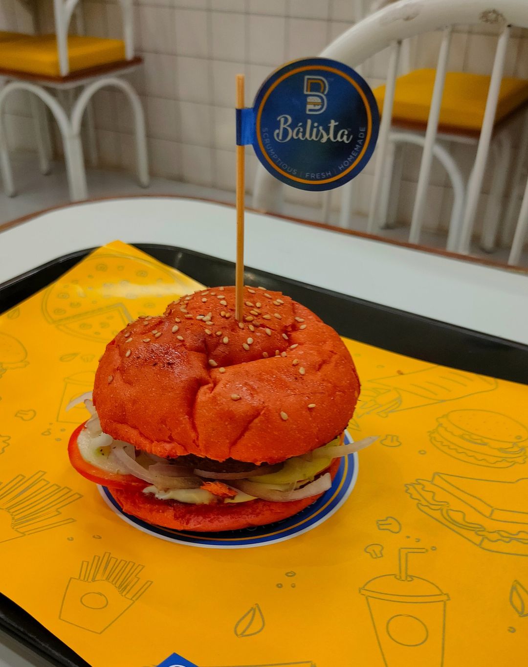 10 Delicious Burger Places In Ahmedabad 7 A delicious-looking burger on a yellow plate with a Balista flag.