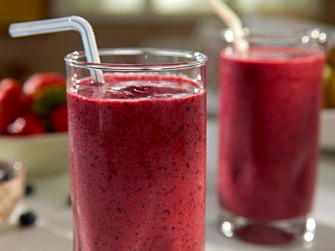 An image of Berry smoothies in glasses. One is in-focus and other is out-focused. The smoothies are served with straws.