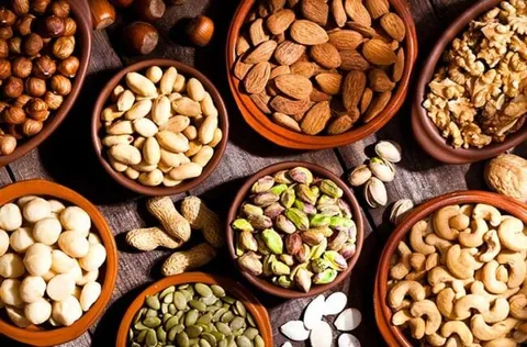 Image of different type of nuts like almonds, walnuts, or pistachios in bowls.