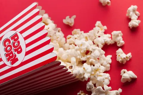 Image of popcorn in a paper container and there's also content on the red-ish background.