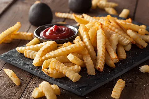 An image of Crinkle Cut Fries served in a plate with ketchup.