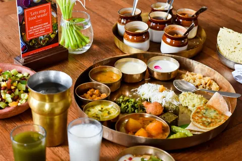 An image of Agashiye - The House of MG's Gujarati Thali served in several dishes, jars, glasses and bowls including a wide variety of Gujarati food.
