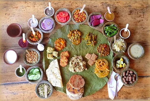 Image of Vishalla's Gujarati Thali served on a huge leaf and several bowls and glasses.
